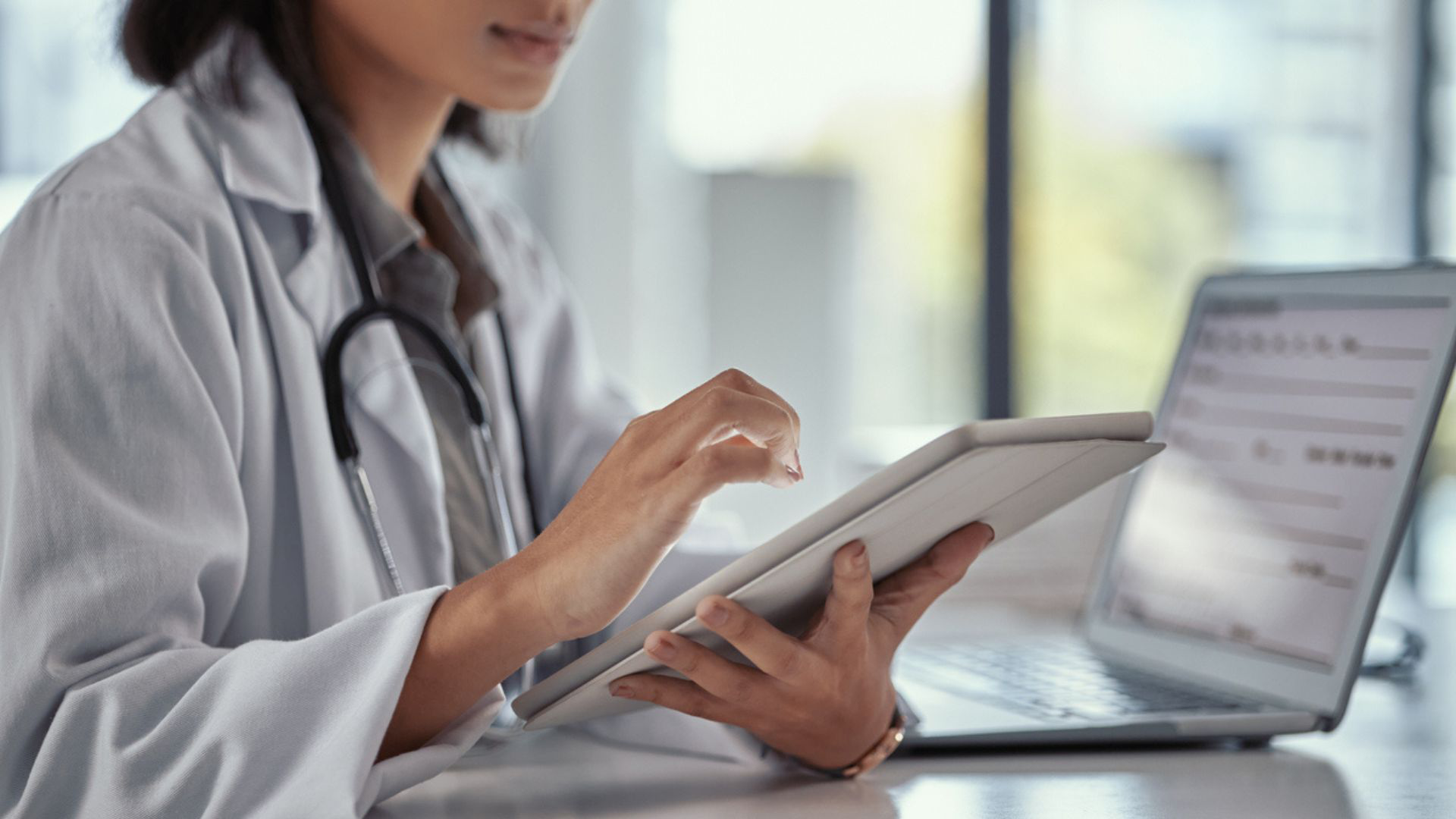 Doctor looking at tablet and computer using payment gateways