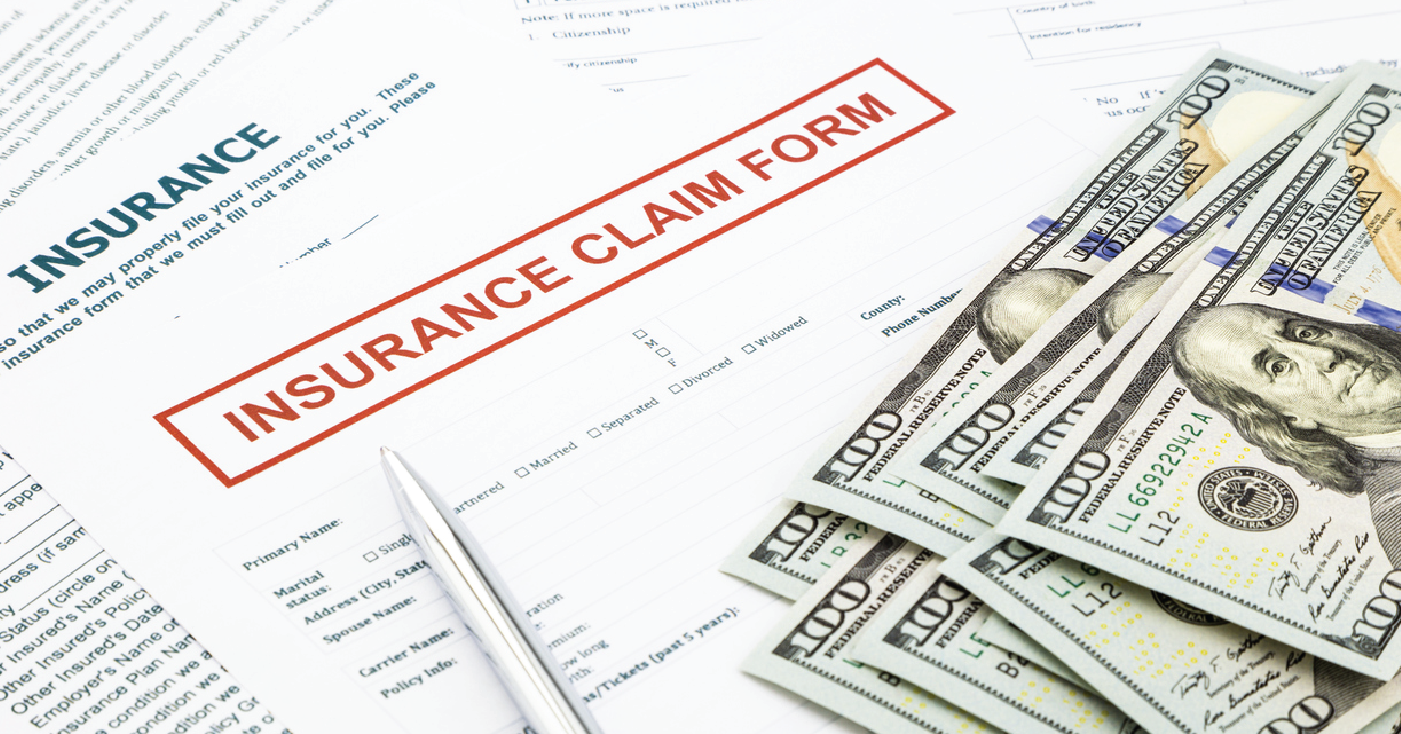 Managing insurance reimbursements - Insurance claim forms on a table with hundred dollar bills.
