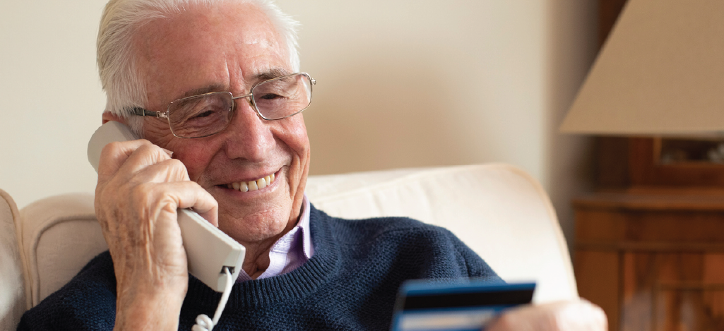 Providing billing reminders for senior patients - Senior man holding a credit card while on the phone.