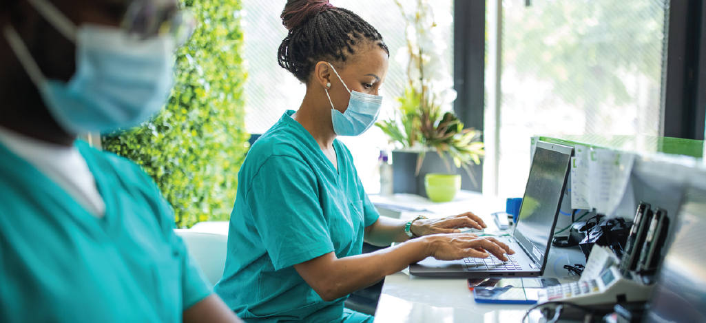 Modern medical practice management - Two nurses using computers to input patient data.