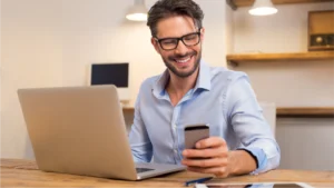 Man looking at phone and computer representing multichannel billing