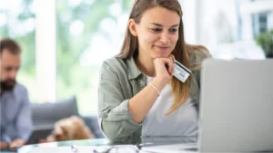 Woman looking at computer with credit card in hand looking at payment options