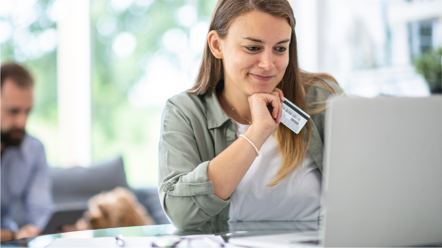 Woman looking at computer with credit card in hand looking at payment options