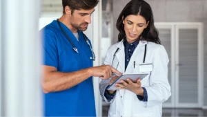 Two doctors talking about an all-in-one billing software while looking at a tablet