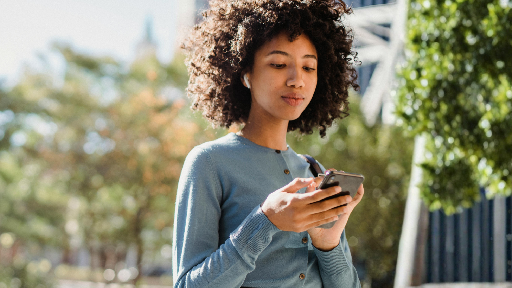 A woman looking at her phone using a text to pay tool to pay her bill