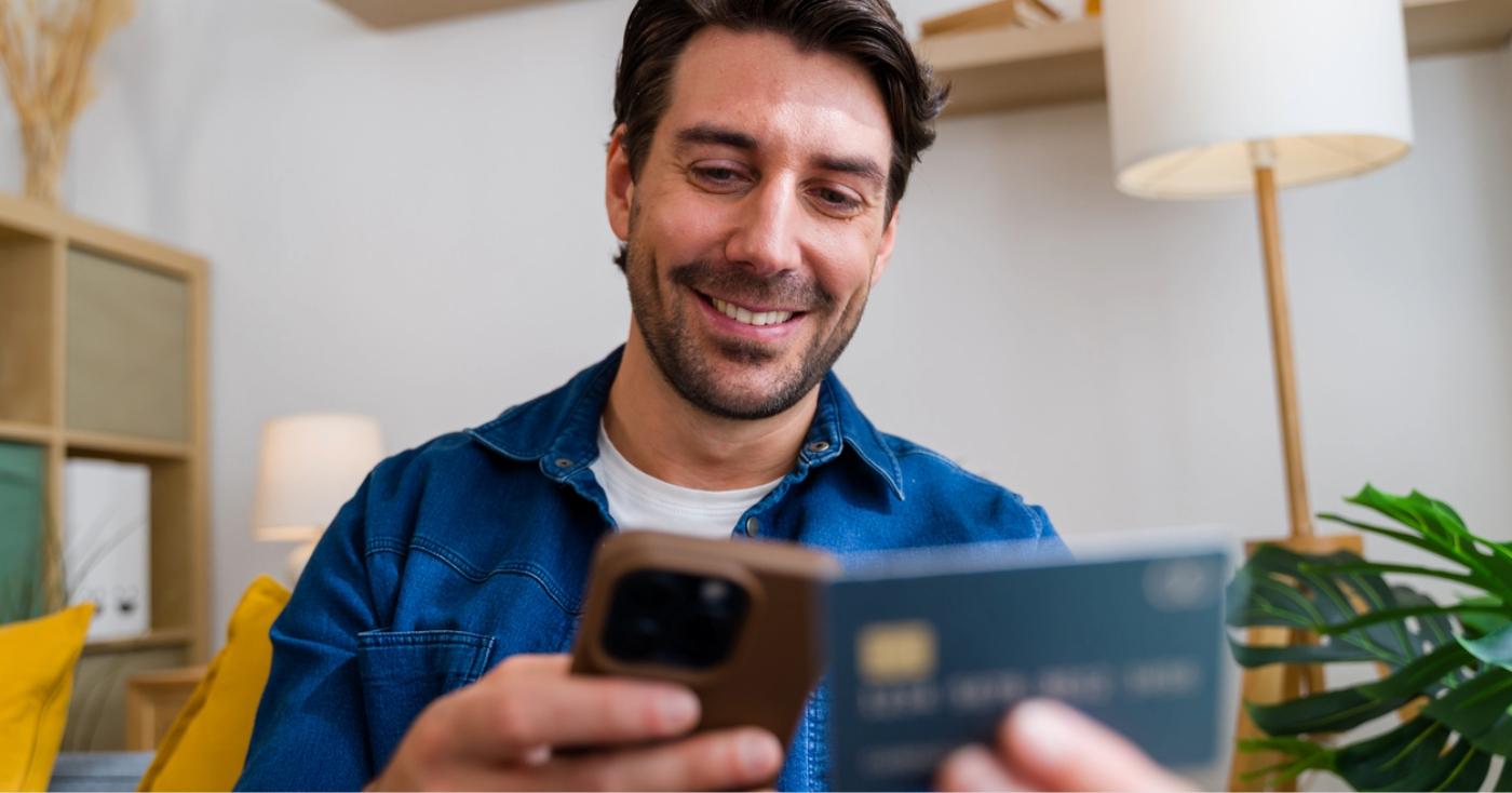 Text to Pay - A man at home using his smartphone and credit card to pay for his medical bill online.
