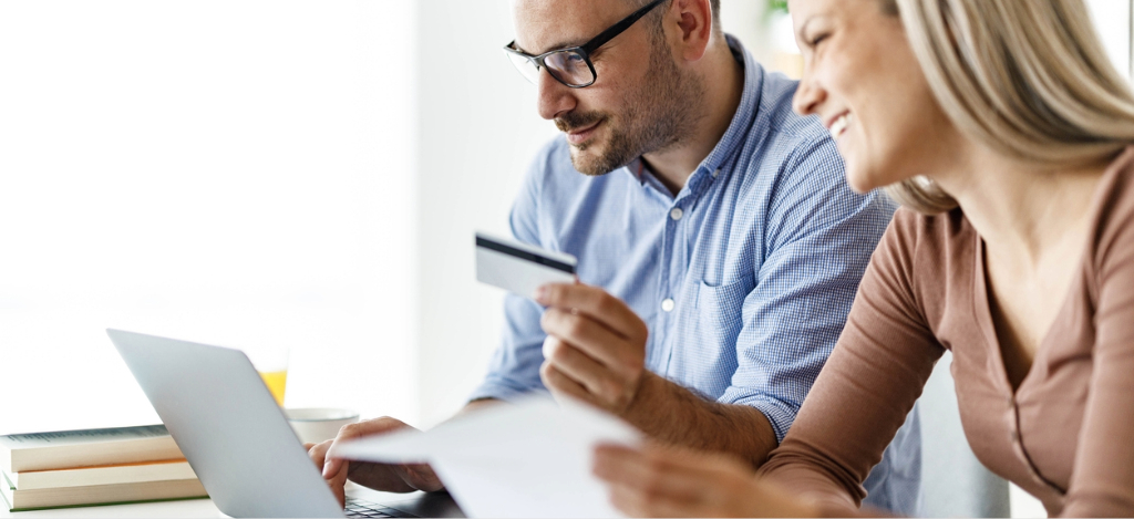 All-in-one communication - A couple at home paying for their medical bills using a laptop and a credit card.