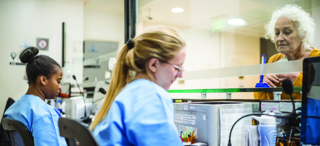 Offering multiple methods to pay - A female medical professional assisting a senior woman in paying her medical bill.