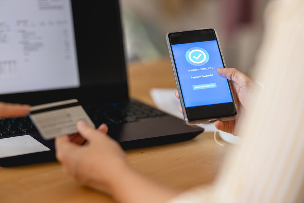 Adopting healthcare payment trends - A woman paying her medical bill using her smartphone and credit card.