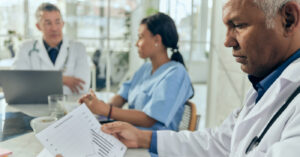 Outsourcing revenue cycle management - A male doctor checking a printed copy of their practice’s revenue.