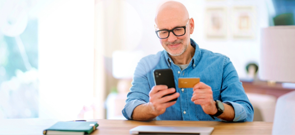 A man at home paying his online medical bill using his smartphone and credit card.