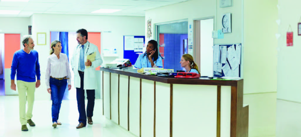 Improving patient experience - A male doctor walking with patients in a hospital.