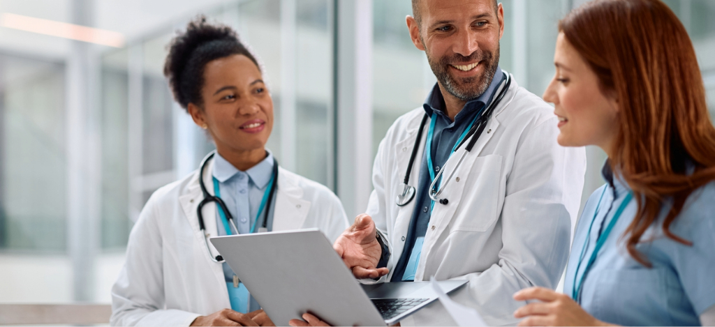 Best RPA software - A male doctor holding a laptop while discussing automated workflows with his colleagues.