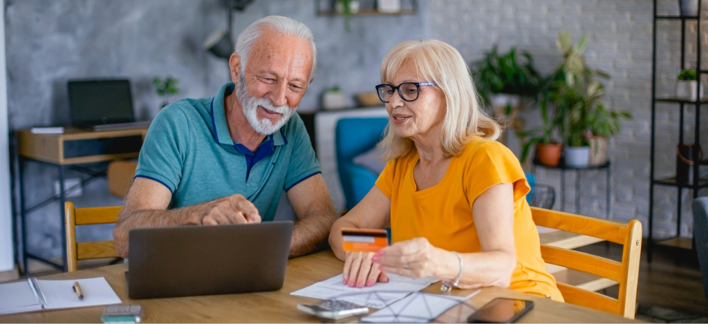 EHR integration - A senior couple at home using their credit card and laptop to pay for their medical bills.