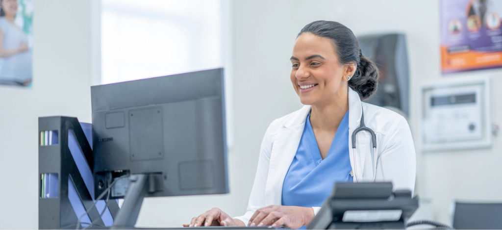 A female doctor in an office using a computer to check patient records.