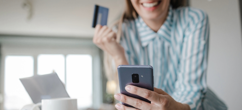 AI medical billing - A woman at home checking and paying her medical bills using her smartphone.