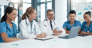 Medical office staff solutions - A team of doctors looking at a laptop while discussing how to improve practice operations.