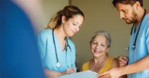 Changing your patient engagement strategies - Two healthcare professionals assisting a senior woman during her medical appointment.