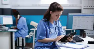Revenue cycle optimization techniques - A female nurse in a clinic using computers to check patient information