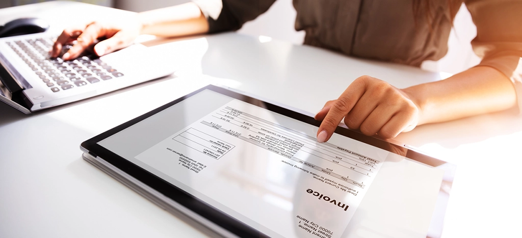 Female medical practitioner preparing a patient invoice using a digital tablet.