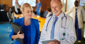 Outsourcing medical billing - A male doctor and a businesswoman discussing hospital billing solutions.
