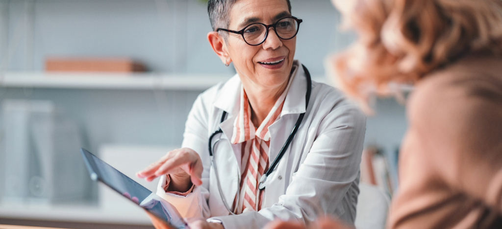 High-deductible health plans - A female doctor using a tablet device to explain medical charges to her patient.