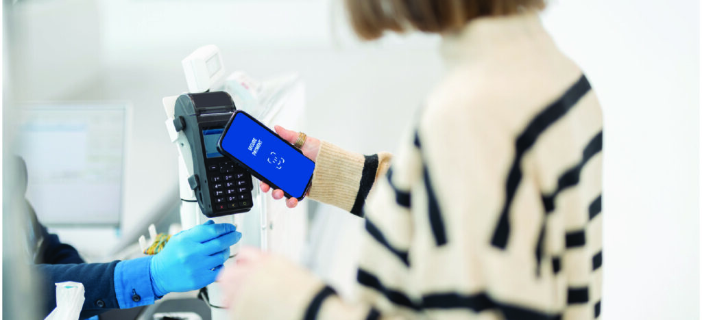 Woman paying contactlessly using a smartphone in a healthcare facility.