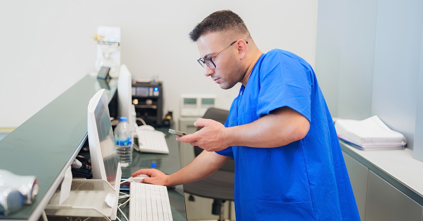 Healthcare staff using a mobile phone and the reception desktop pc.