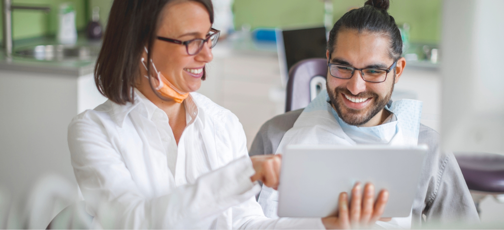 Dental software - A female dentist using a tablet device to show her male patient his dental bill.