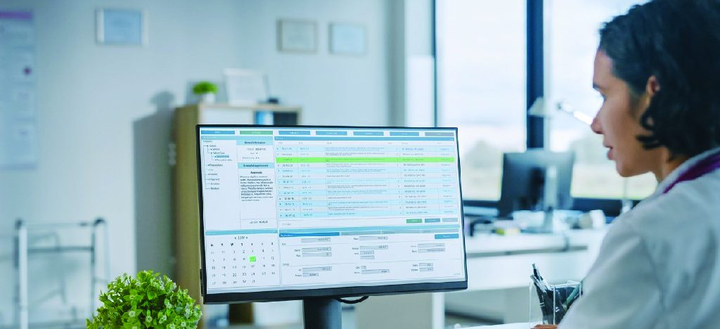 Managing medical debt collection information - A female doctor looking at patient information displayed on a computer.