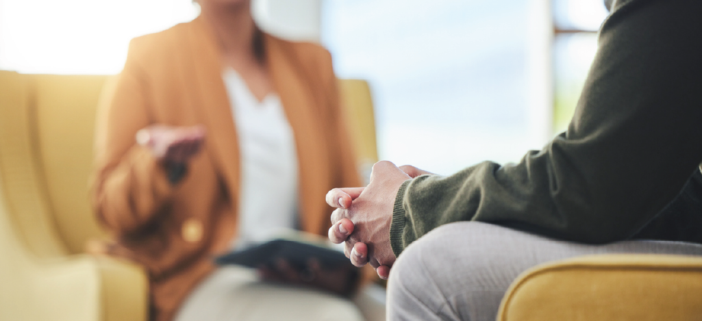 Choosing mental health billing software - A female mental health practitioner speaking to her male client in a clinic.