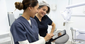 Dental software - Two female dentists in a dental office looking at a tablet device showing their billing and collections software.