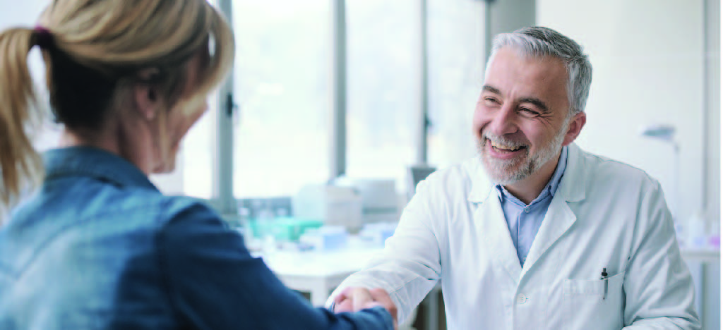 Improving patient experience - A female patient shaking hands with her male doctor in a clinic.