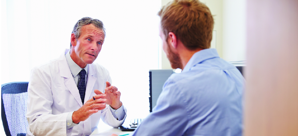  Improving patient financial responsibility - A male doctor speaking to a male patient during a medical consultation.