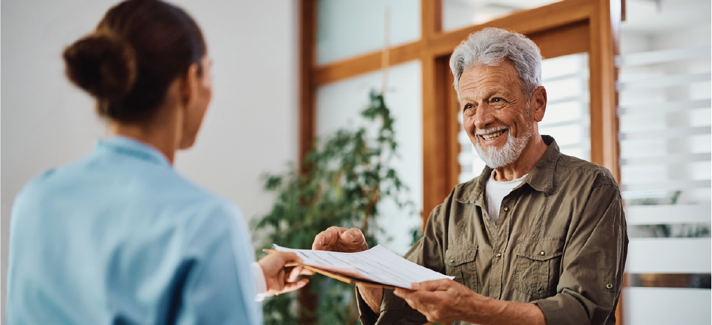 Patient financing options - A female medical staff assisting a senior man during his medical appointment.