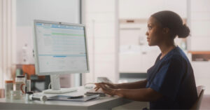 All-in-one communication - A female hospital staff member using a computer to communicate patient bills.