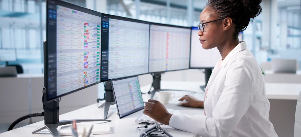RCM outsourcing companies - A female doctor looking at her practice’s billing software through different computer screens.