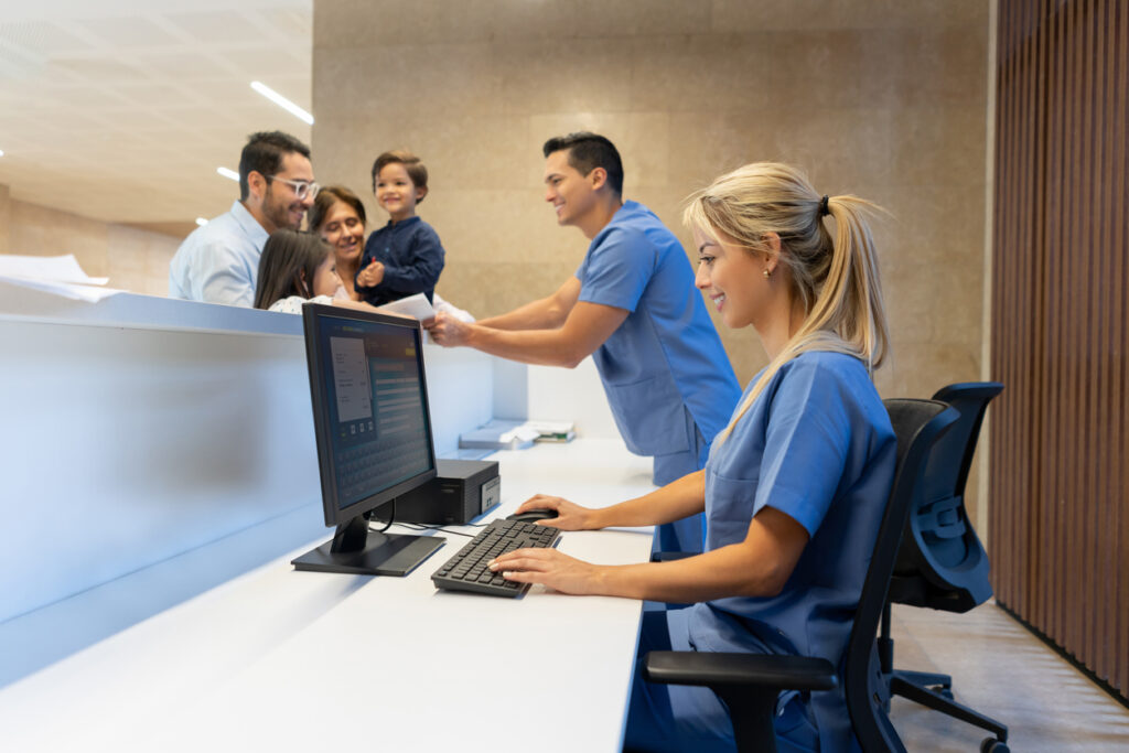 Using updated healthcare technology tools - Hospital staff using a computer while assisting patients.