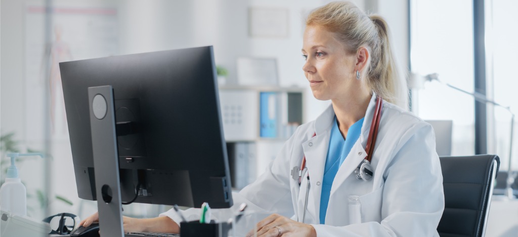 Pre-visit billing for healthcare and dental practices - A female doctor analyzing patient payments using a computer.