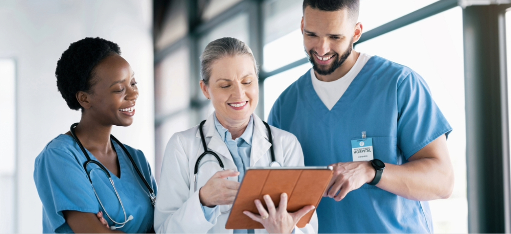 Revenue cycle partner - Three medical professionals reviewing their hospital software through a tablet device.