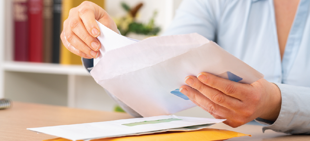 Including personalized patient statement inserts - A woman at home opening an envelope containing her medical bill.