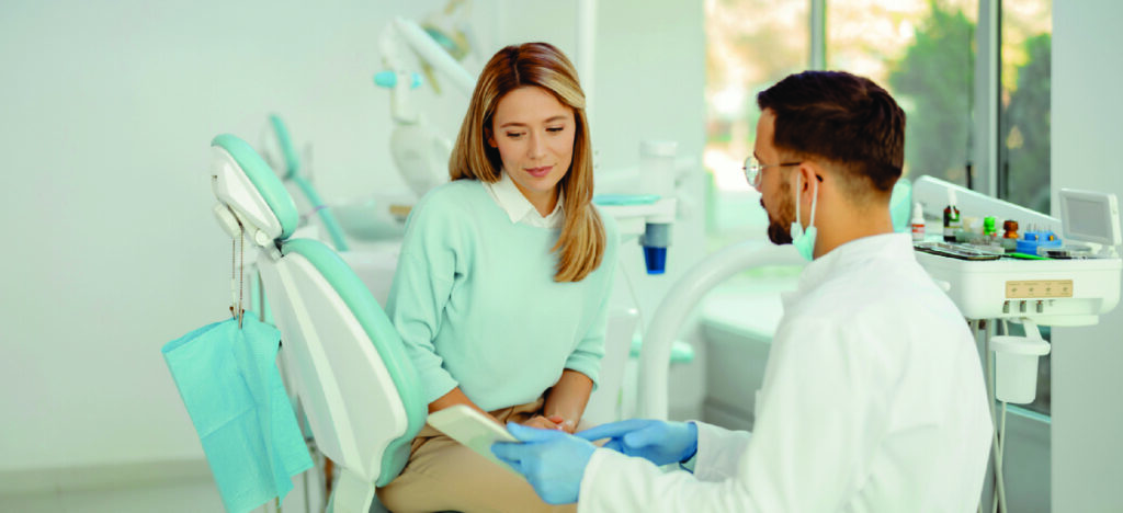 Affordable dental care financing - A male dentist explaining treatment plans to his female patient.