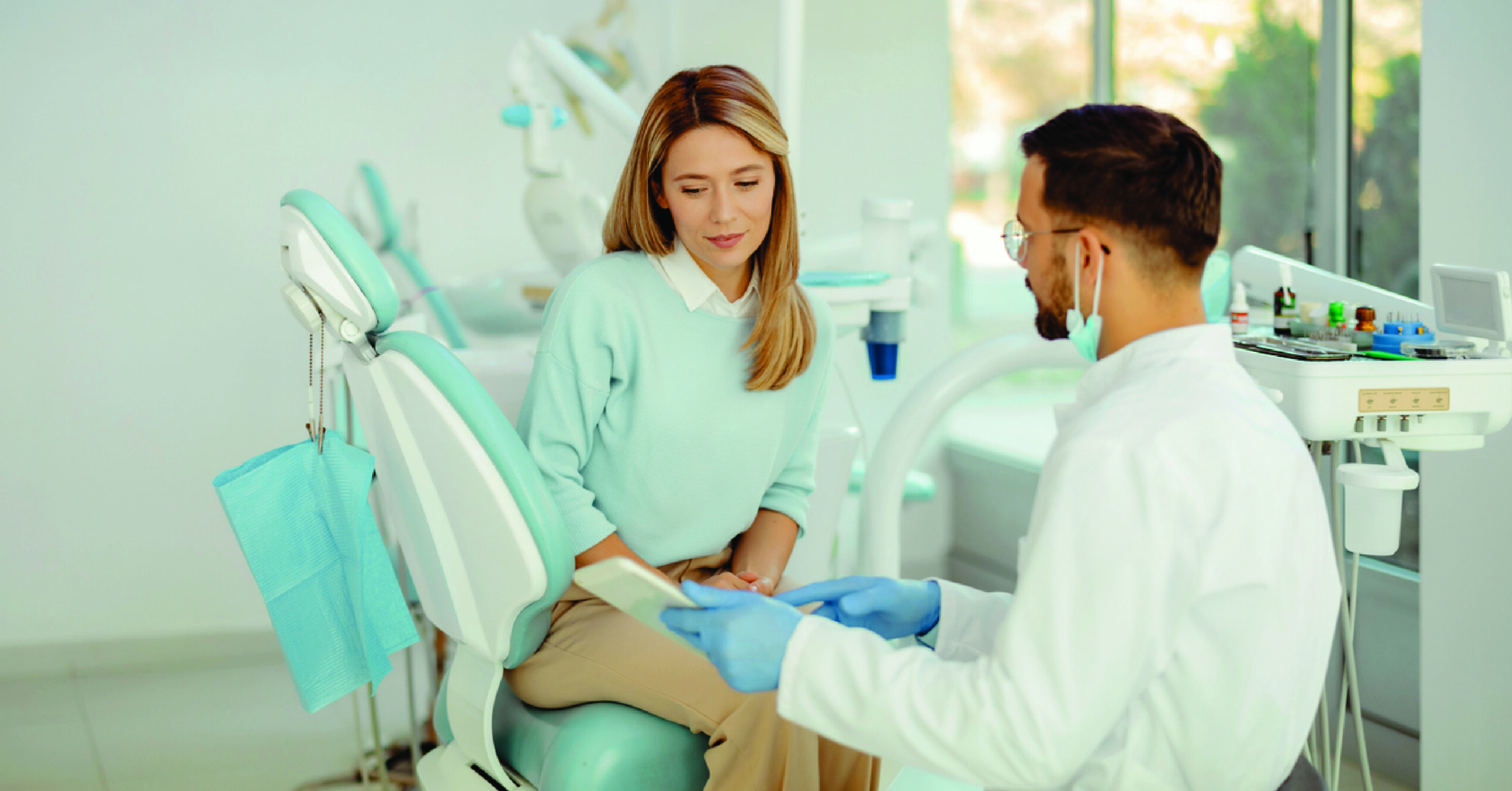 Affordable dental care financing - A male dentist explaining treatment plans to his female patient.