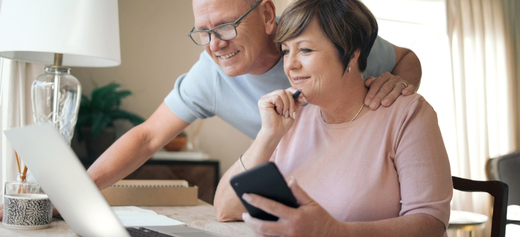 Billing checklist - A senior couple at home using their laptop and smartphone to pay for their medical bill.