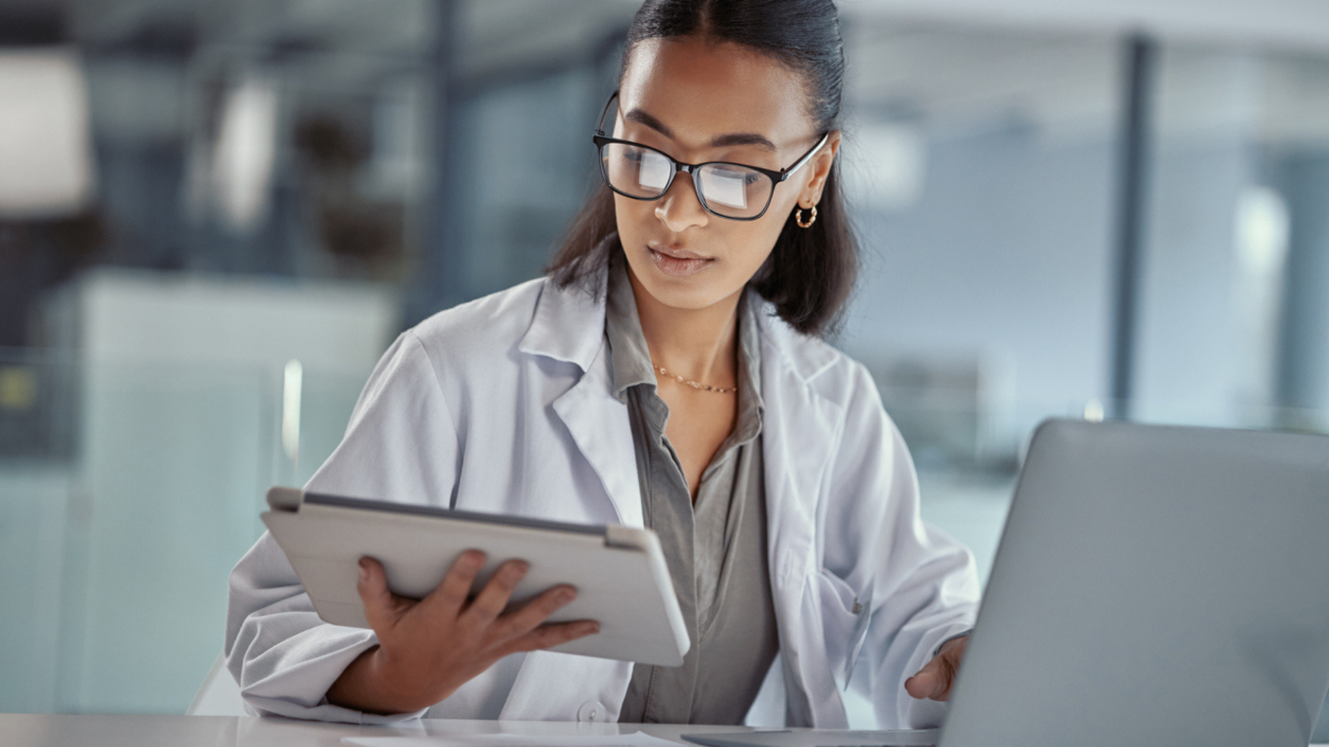 Woman doctor implementing medical billing software to her computer and tablet.