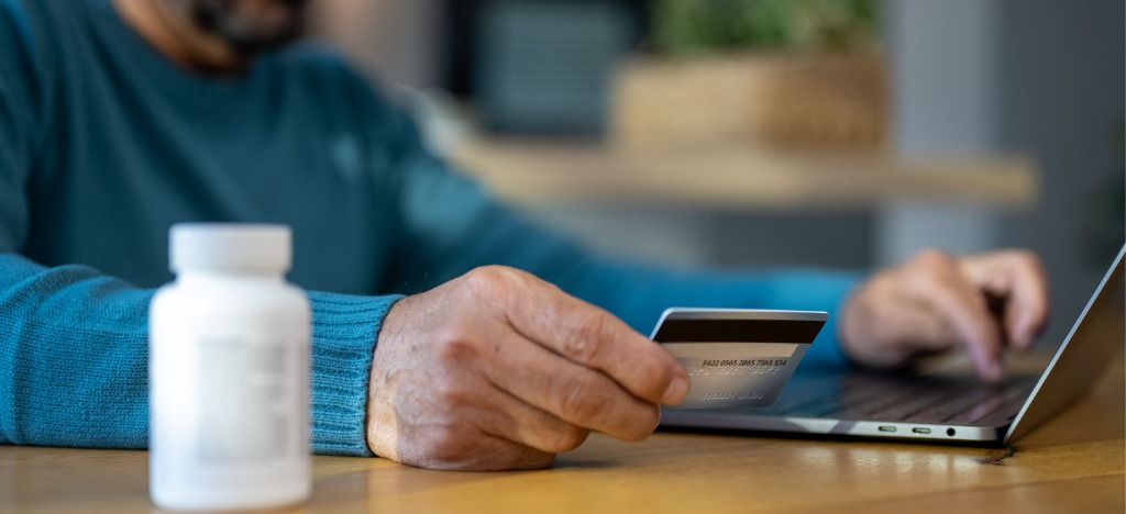 Payment journey inclusions - A senior man holding a credit card while paying his medical bills online.