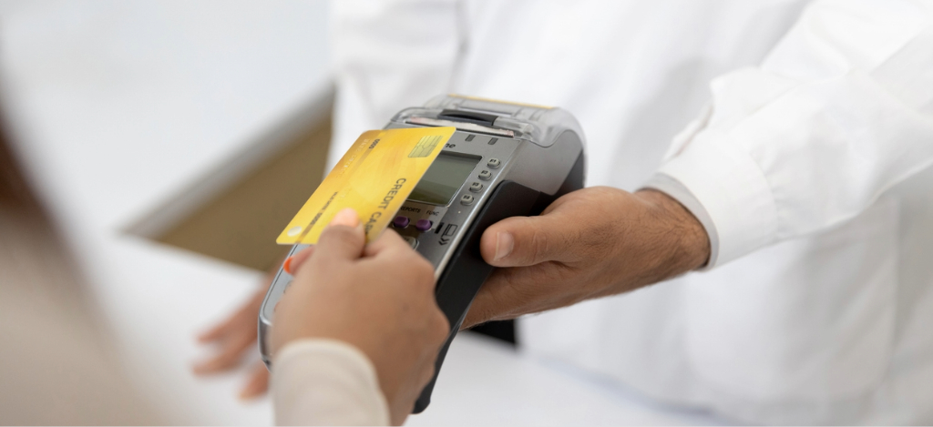 Patient payment solutions - A female patient tapping her credit card on a reader held by a doctor.