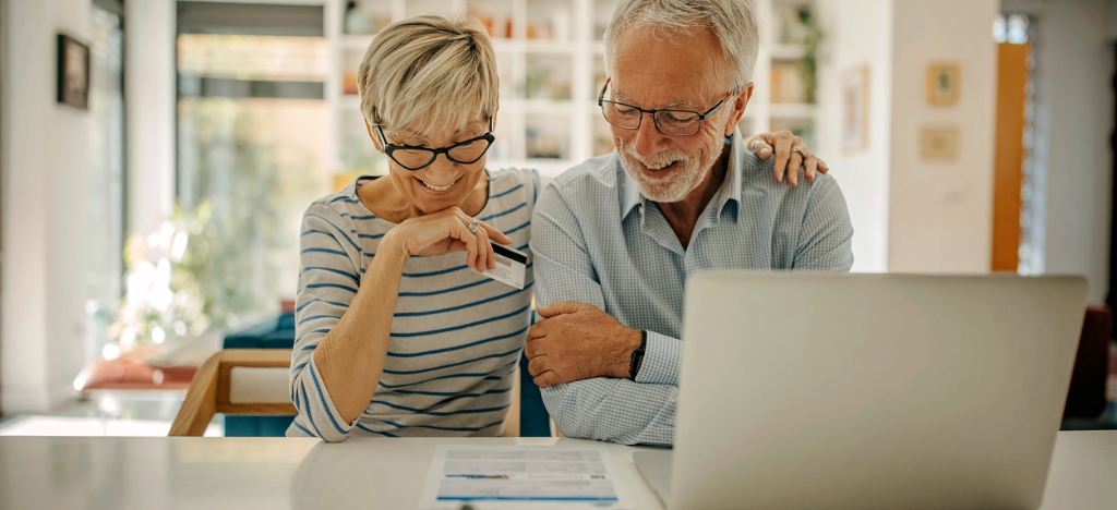 A happy senior couple at home looking at their printed medical bill.
