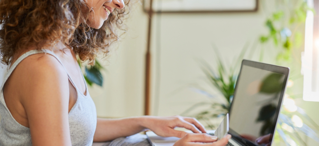 Plastic surgery clinics - A woman at home booking and paying for her plastic surgery appointment using a laptop and a credit card.