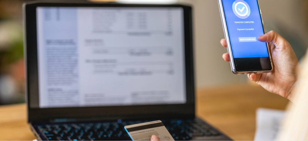 RCM companies - A woman using her credit card and smartphone while paying for her medical bill.